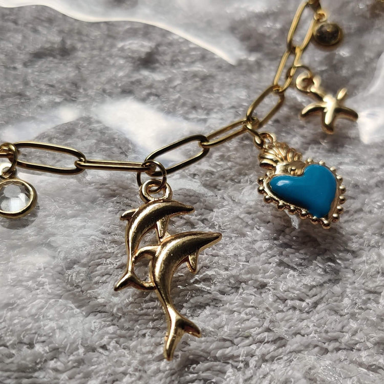 Zoom sur les charms du collier doré Danse Océane – coeur, étoile de mer, dauphin – Roxy Paris