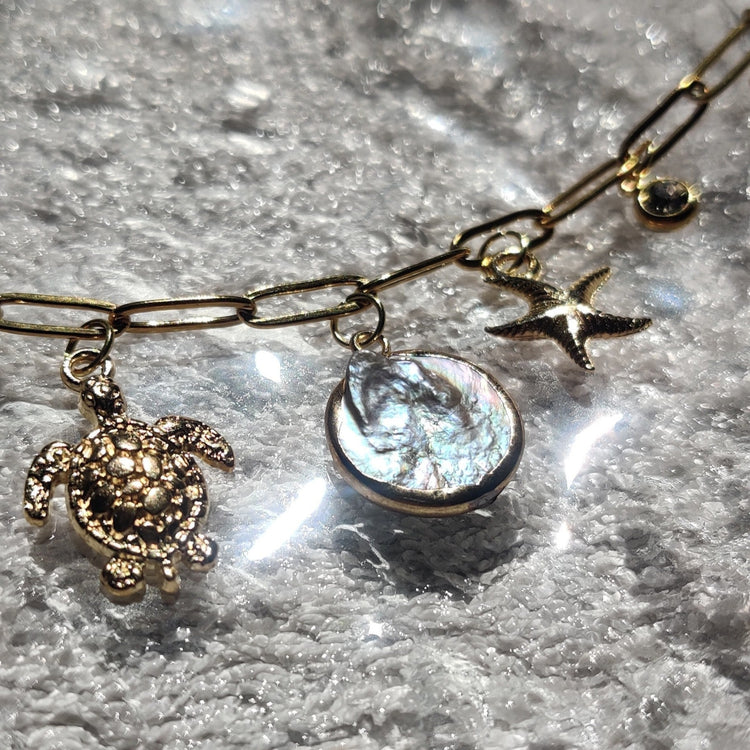 Zoom sur les charms pierre d'eau douce, tortue & étoile de mer du collier doré - Roxy Paris