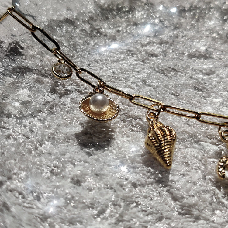 Zoom sur les charms perle & coquillage du collier doré - Roxy Paris