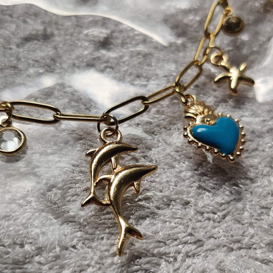 Zoom sur les charms du collier doré Danse Océane – coeur, étoile de mer, dauphin – Roxy Paris