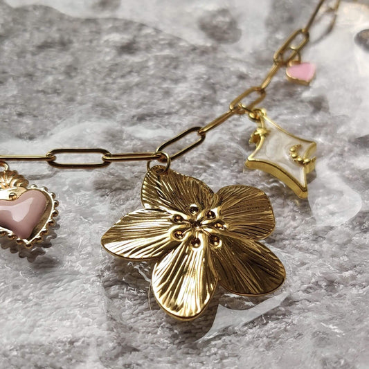 Zoom sur les charms du collier doré éclat floral – marguerite, coeur, étoile – Roxy Paris