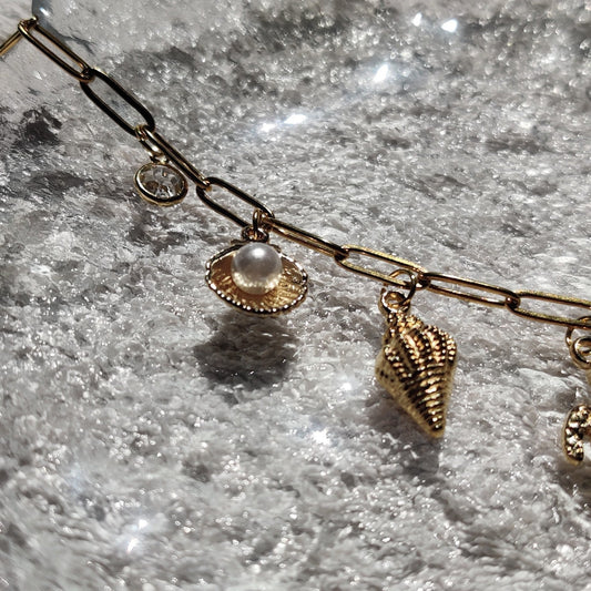 Zoom sur les charms perle & coquillage du collier doré - Roxy Paris