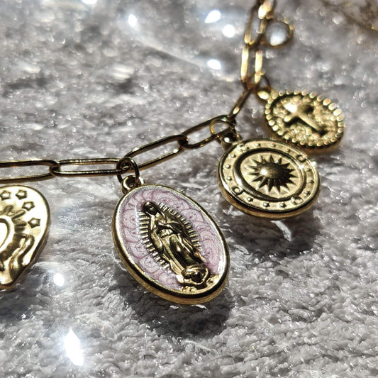 Zoom sur les charms croix, Vierge Marie et soleil du collier doré - Roxy Paris